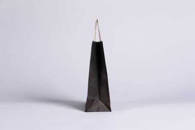 Gri arkaplanda bir siyah kağıt alışveriş çantası