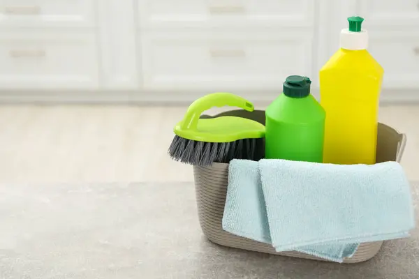Different cleaning supplies in basket on table. Space for text