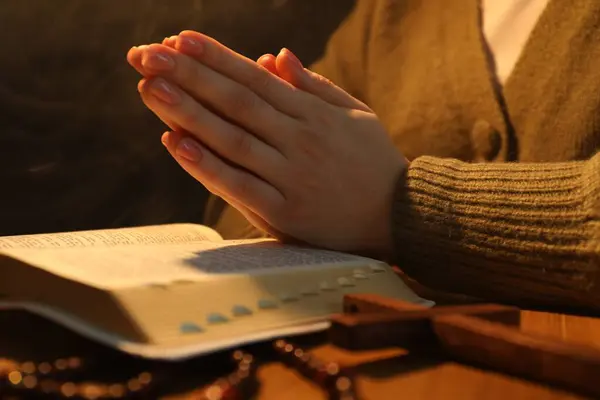 Woman with Bible praying at table, closeup