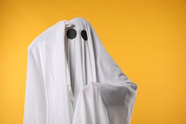 Ürkütücü hayalet. Sarı arka planda beyaz çarşafla kaplanmış kişi