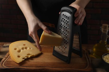 Ahşap masada peynir rendeleyen kadın, yakın plan.