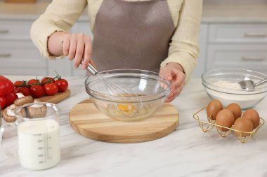 Açık mermer masada yumurta çırpan bir kadın, yakın plan.