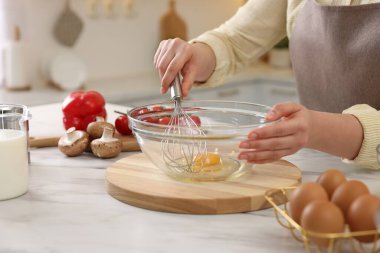 Açık mermer masada yumurta çırpan bir kadın, yakın plan.