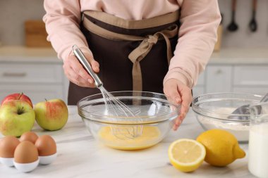 Açık mermer masada yumurta çırpan bir kadın, yakın plan.