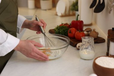 Kapalı mekânda yumurta çırpan bir kadın.