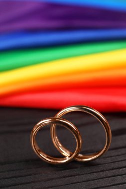 Gökkuşağı LGBT bayrağı ve siyah ahşap arka planda alyanslar, yakın plan