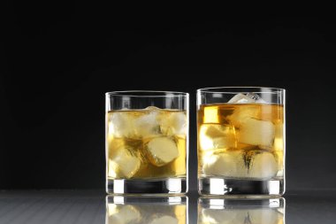 Aynalı masada buzlu lezzetli viski, siyah arka planda, yakın planda.