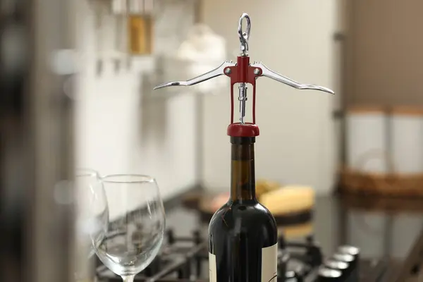 Wine bottle with metal corkscrew in kitchen