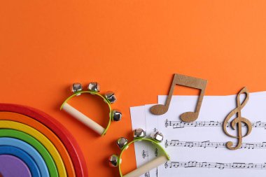 Bebek şarkıları yapmak için aletler. Turuncu arka planda çocuklar için tef çalan düz bir kompozisyon. Metin için boşluk