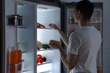 Peynirli adam geceleri mutfaktaki buzdolabından sosis çıkarıyor.