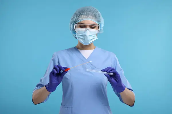 Laboratory testing. Doctor with cotton swab and tube on light blue background
