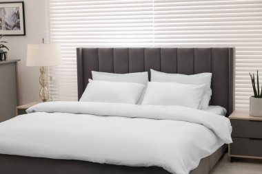 Şık bir yatak odasında büyük bir yatak ve lamba. İç tasarım