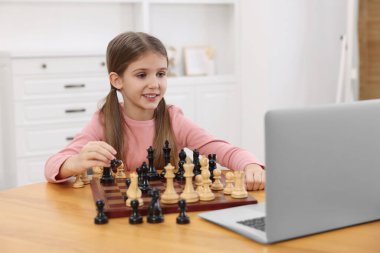 Evde online öğretmenle satranç oynamayı öğrenen tatlı bir kız.