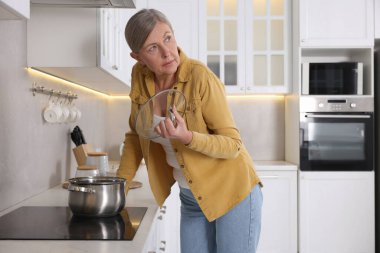Menopoz. Mutfakta yemek pişirirken sıcak çarpması yaşayan bir kadın.