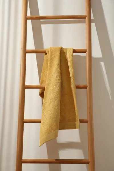 Yellow towel hanging on wooden ladder indoors