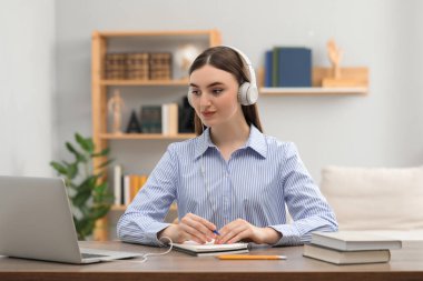 E-öğrenme. İçerideki masada ders alan bir kadın.