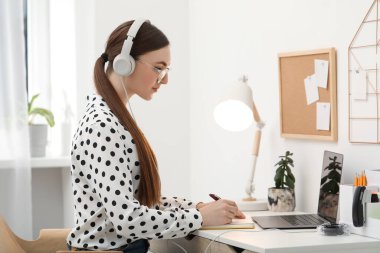 E-öğrenme. İçerideki masada ders alan bir kadın.