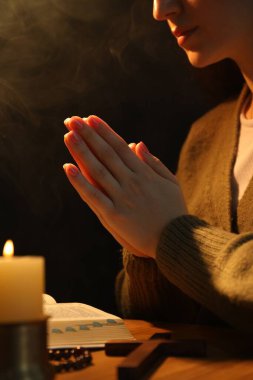 Masada yanan mum ve İncil 'le dua eden kadın, yaklaş.