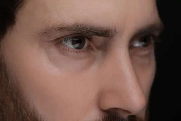 Evil eye. Man with scary eyes on black background, closeup