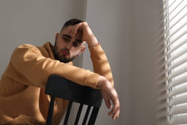 Pencerenin yanındaki sandalyede oturan üzgün adam. Metin için boşluk