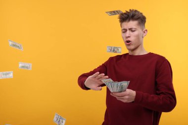 Sarı arka plana dolar atan yakışıklı bir adam.