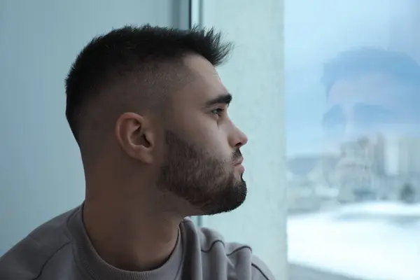 Sad man looking at window at home