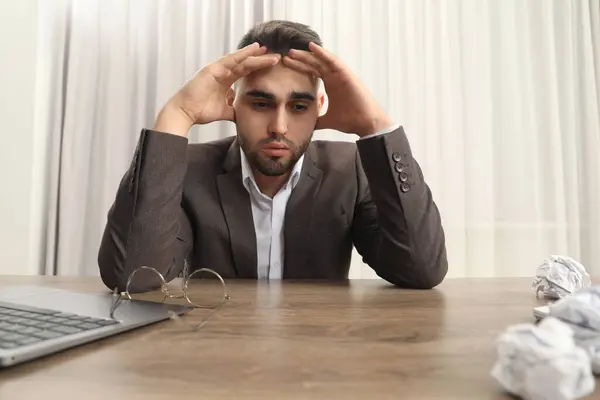 Tired sad businessman sitting at table in office, low angle view