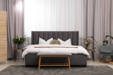 Şık bir yatak odası. Büyük yatak odası, kanepe, lamba ve çiçek.