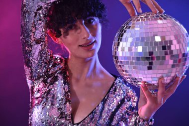 Disko topuyla güzel bir genç kadın. Renkli arka planda, neon ışıklarda poz veriyor. Yakın plan.