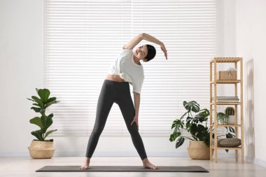 Yoga stüdyosunda mindere uzanan bir kız. Janu Sirsasana poz değişimi