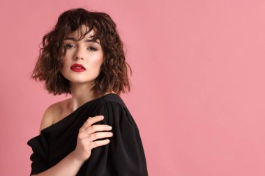 Pembe arka planda dalgalı saç stili olan güzel bir genç kadının portresi. Metin için boşluk