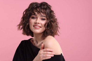 Pembe arka planda dalgalı saç stili olan güzel bir genç kadının portresi. Metin için boşluk