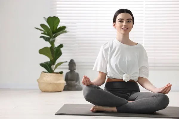 stock image Beautiful girl meditating on mat in yoga studio