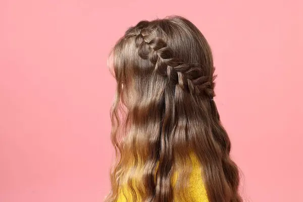 Little girl with braided hair on pink background