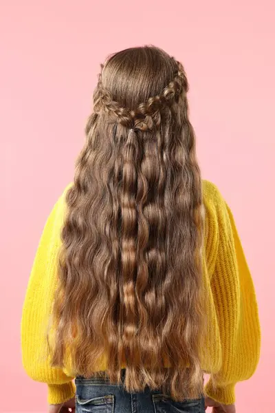 Little girl with braided hair on pink background, back view