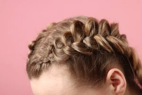 Woman with braided hair on pink background, closeup