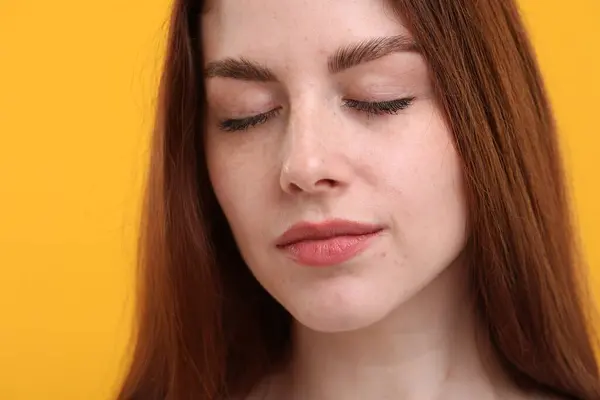 Portrait of beautiful woman with freckles on yellow background, closeup