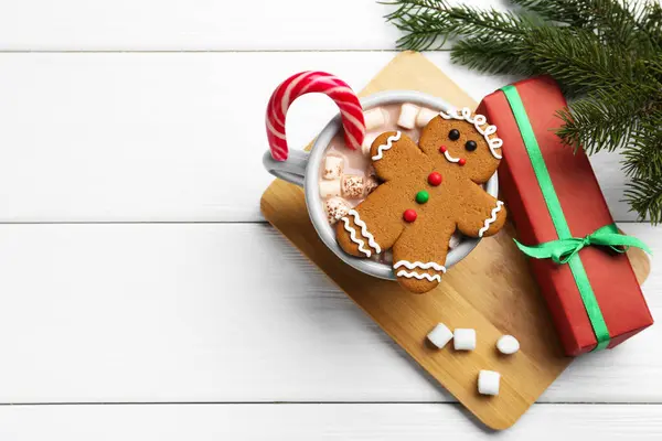 Tasty homemade Christmas cookie, gift and hot chocolate with marshmallows on white wooden table, top view. Space for text
