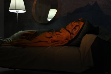 Geceleri kanepede battaniyedeki canavardan saklanan küçük kız.