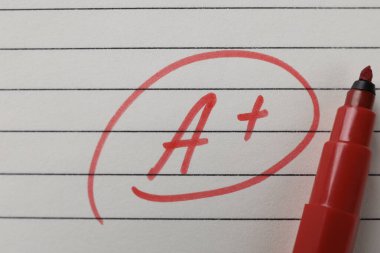 Okul derecesi. Kırmızı harf A artı sembollü defter kağıdı ve işaretleyicisi, üst görünüm