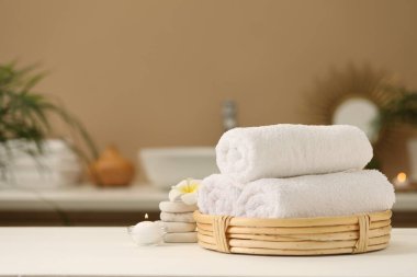 Spa kompozisyonu. Yuvarlak havlular, masaj taşları, yanan mum ve masa başı çiçekleri. Metin için boşluk