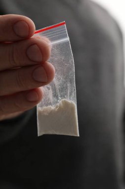 Uyuşturucu bağımlılığı. Arka planda plastik kokain torbası olan adam, yakın plan.
