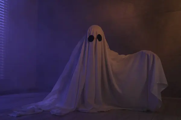 Creepy ghost. Woman covered with sheet in color lights
