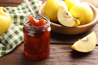 Kavanozda ev yapımı ayva reçeli, ahşap masada kaşık ve meyveler, yakın plan.