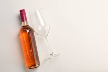 Beyaz arka planda bir şişe pahalı gül şarabı ve şarap kadehi. Metin için boşluk