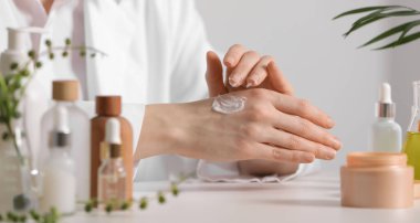 Dermatolog, beyaz masada el kremi sürüyor. Seçici bir odak noktası. Kozmetik ürünü test ediliyor