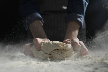 Ekmek yapıyorum. Masada hamur yoğuran kadın, yakın plan.