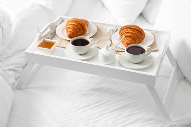 Yatakta servis edilen lezzetli kahvaltı. Taze kruvasan, kahve ve bal.