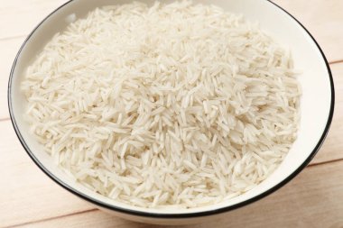 Beyaz ahşap masada, kasede çiğ basmati pilavı, yakın plan.