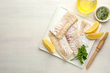 Beyaz ahşap masada baharatlı taze morina filetosu ve limon. Metin için boşluk